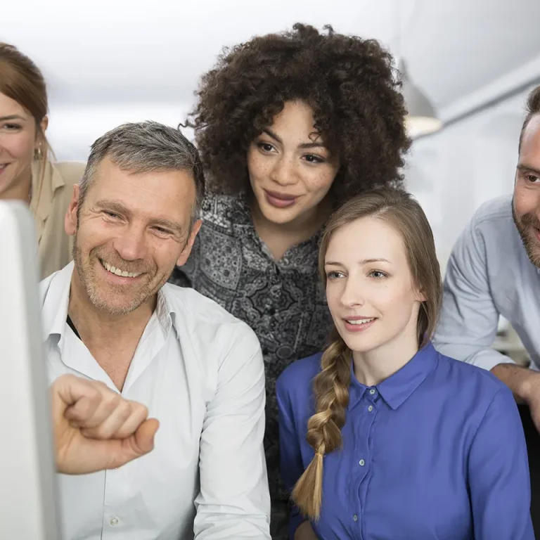 Team members smiling while reviewing logistics operations on screen